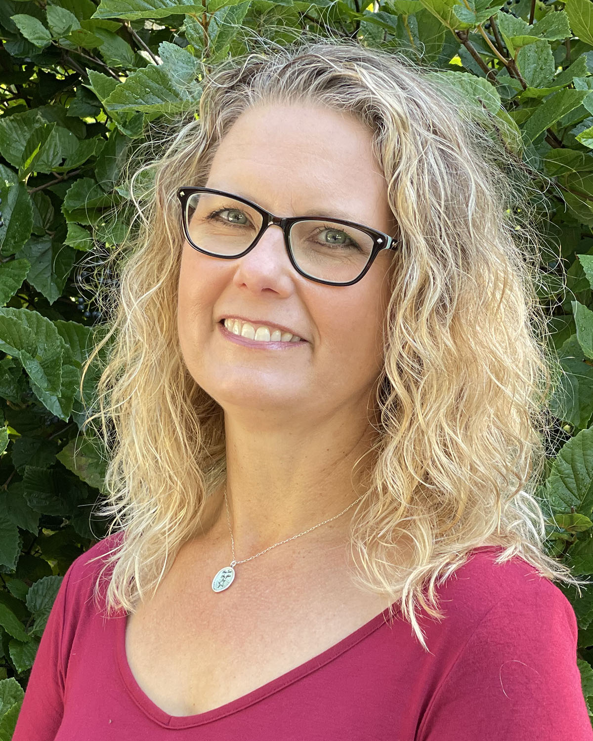 Angie Beyer Headshot (outside with greenery in background)