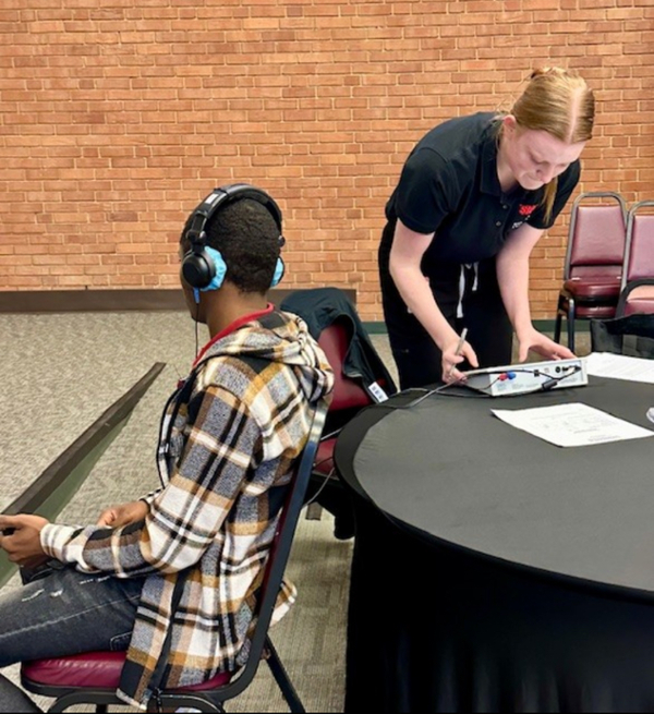 One grad student at table monitoring client with headphones on