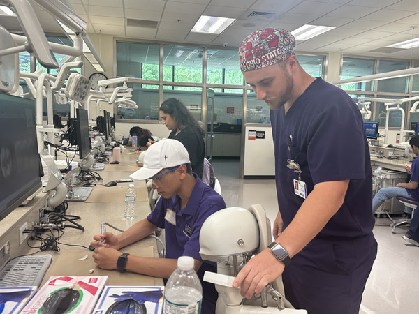 Dental instructor stands by table of students