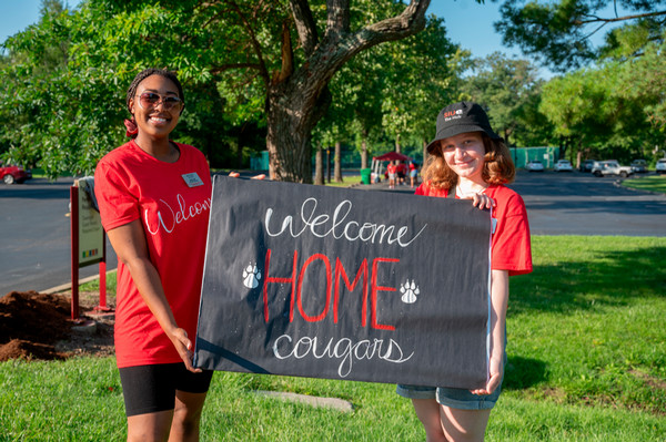 Students hold large Welcome Home Cougars sign