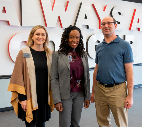 Three people standing with Kia Johnon in the middle