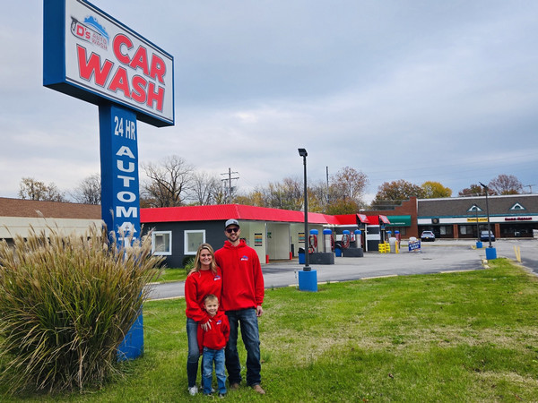 Nick and Amy Deiter pose for photo in front of auto wash establishment